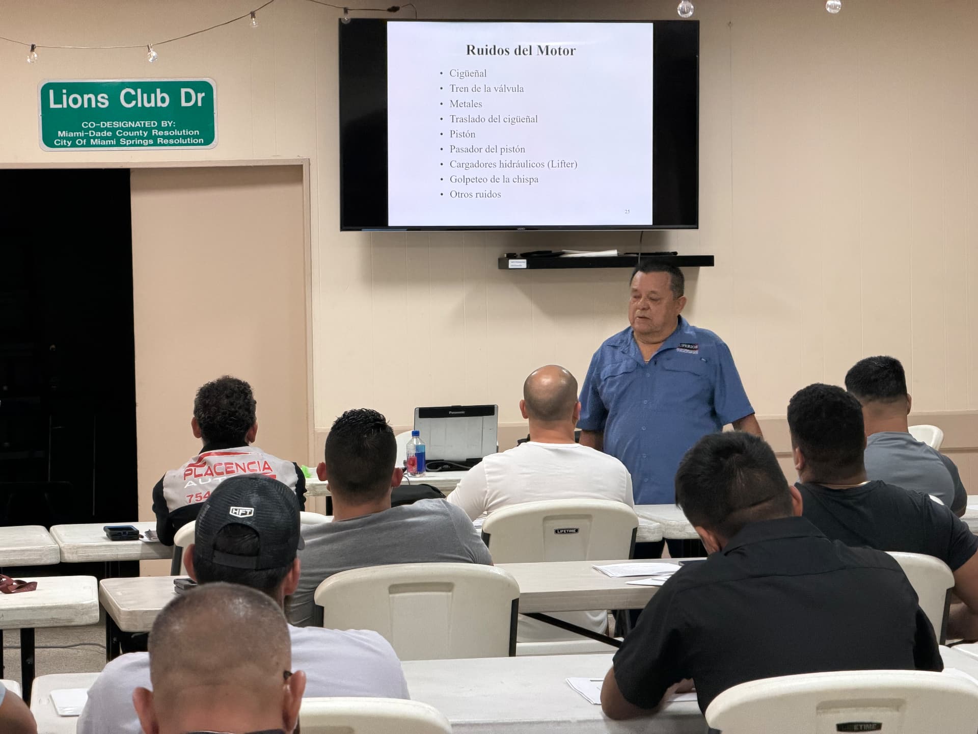 Instructor teaching engine noise diagnosis on screen to a full class